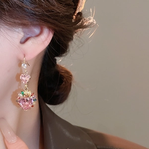 Close-up of elegant pink heart-shaped earrings with gold setting worn by a model
