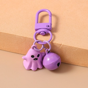 Close-up of a cute purple cartoon ghost keychain with a matching metal bell and ring
