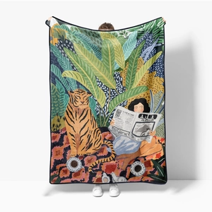 Detail of soft flannel blanket featuring jungle tiger illustration and reader reading Le Monde