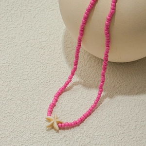 Bohemian style pink bead necklace with a beige starfish pendant on a minimalist background