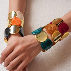Dettaglio di bracciali elastici con cerchi in resina colorata e pezzi in metallo dorato
