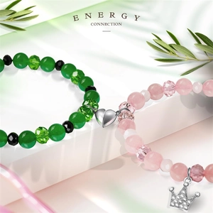 Magnetic crown friendship bracelets with green and pink beads on a white pedestal