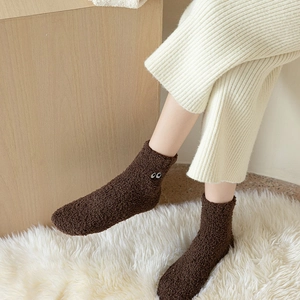 Detailed texture of brown coral fleece socks with cute eye embroidery for winter warmth