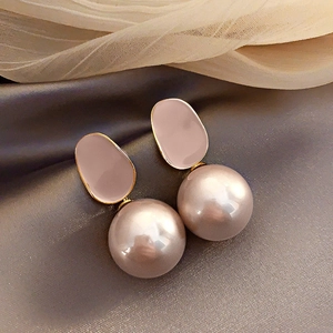 Macro shot of elegant French pearl pendant earrings with pink resin on dark satin fabric