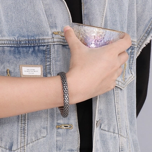 Detail view of a vintage silver punk steel bracelet with snake scale texture on a wrist