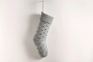 Detail of light grey knit Christmas stocking with a textured fish scale pattern weave