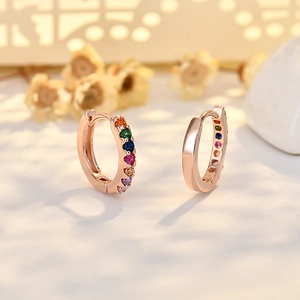 Rose gold hoop earrings with multi-colored cubic zirconia stones on soft floral backdrop