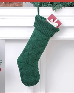 Green knit Christmas stocking on fireplace with a red gift box inside, festive decor