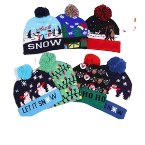 Variety of LED knitted Christmas beanies with festive patterns and colorful pom-poms