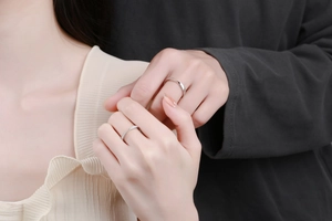 Close-up of S925 silver couple rings with a wave-shaped diamond band and a smooth male band
