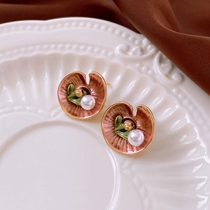 Detail view of retro lotus flower earring with enamel finish and white faux pearl