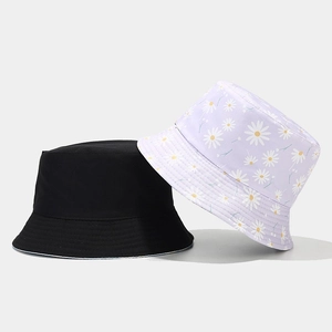Detail view of cotton bucket hats in solid black and purple daisy print pattern