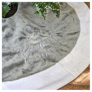 Close-up of plush Christmas tree skirt with festive embroidery on soft white faux fur