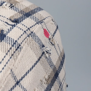 Close-up of vintage plaid fabric texture with distressed edges and red heart detail