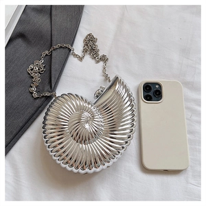 Macro detail of silver snail shell evening clutch with polished spiral texture and chain