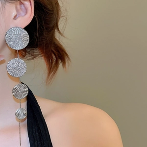 Detail of silver drop earrings with four textured round metallic discs and long tassels
