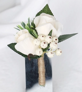 Detailed view of white artificial rose boutonniere with green leaves and burlap twine handle