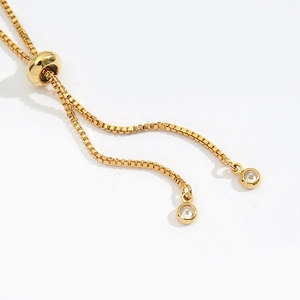 Detail of golden box chain featuring an adjustable slider clasp and clear zircon charms