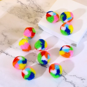 Soft plush rainbow cat toy balls in assorted colors on a white marble background