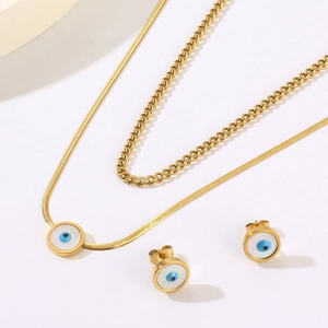 Detail view of gold double-layer necklace and earrings set with white shell evil eye motifs
