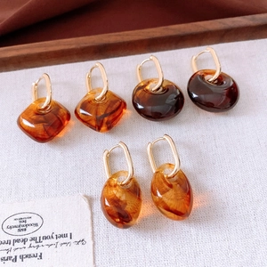 Close-up of vintage tortoiseshell acrylic earrings with gold clips on cream textured fabric