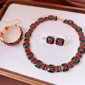 Vintage gold jewelry set with green square base and pink stones in a wooden tray