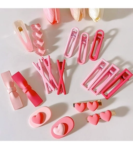 Flat lay of pink Y2K style resin hair clips in heart and bow shapes on white background