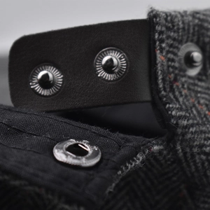 Macro view of herringbone fabric and leather patchwork with silver metal snap buttons