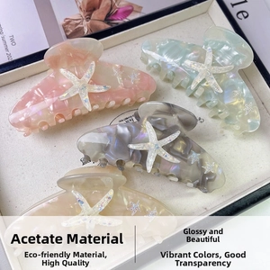 Detail of four acetate starfish claw clips in pastel colors with marble texture on a tray