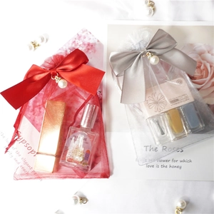 Detail of red and grey organza gift bags featuring pearl charms and ribbon bows