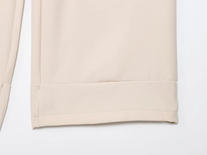 Close-up of rolled hem stitching and beige woven fabric texture of these long pants