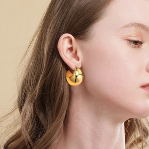 Detailed side view of a large gold C-shaped hollow earring on a model for scale