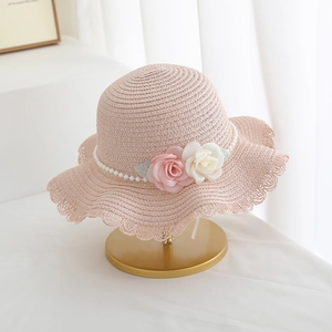 Close-up of pink woven sun hat featuring 3D roses, pearl chain and scallop edge details
