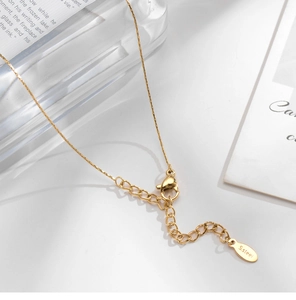 Detailed macro view of the 18K gold-plated lobster clasp and S.steel engraved tag