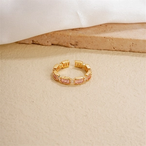 Elegant gold plated open ring with baguette cut pink zircons on a textured stone base
