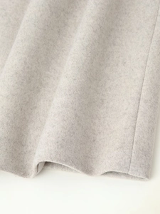 Close-up detail of grey wool blend overcoat fabric texture with neat stitching and hem