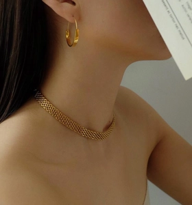Elegante collana a maglie grosse dorate e orecchini rotondi su una modella