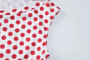 Détails du motif à pois rouges sur tissu blanc et coutures soignées du col rond féminin
