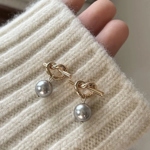 Elegant 925 sterling silver knotted earrings with gray pearl drops on beige knit background