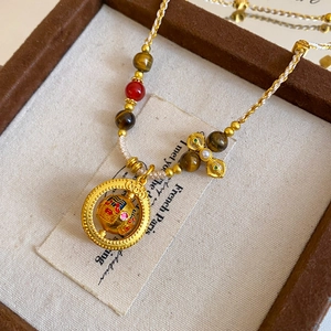 Macro detail of Chinese style gold pendant with red enamel on a white woven rope cord