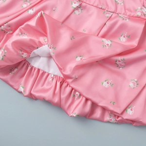 Detail of pink floral satin skirt featuring ruffled hem and delicate rose patterns