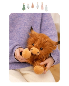 Close-up of a fluffy brown highland cow plush toy being held, showing soft long hair texture