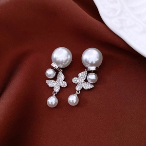 Détail de boucles d'oreilles papillon en perles avec cristaux sur fond en velours