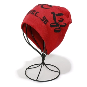 Detail of red winter knit beanie with black jacquard lettering on a display stand