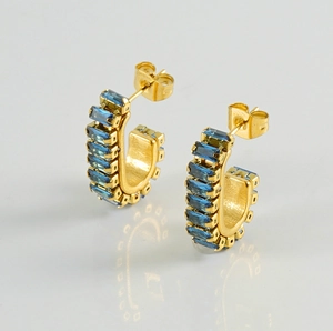 Detailed view of gold C-shaped earrings set with rectangular blue zircon stones