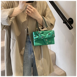 Detail of green satin evening bag featuring a rhinestone bow and elegant metal chain