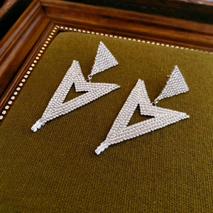 Detail of irregular triangle zircon earrings with silver needle on green velvet stand
