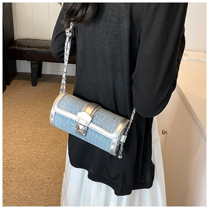 Blue denim texture cylinder bag with silver chain strap shown on a model's shoulder