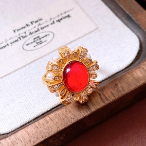 Detailed close-up of a vintage 24k gold-plated oval red gem ring with pearls and floral petals