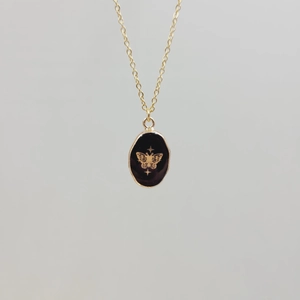Detailed close-up of a gold stainless steel necklace with a black enamel butterfly pendant